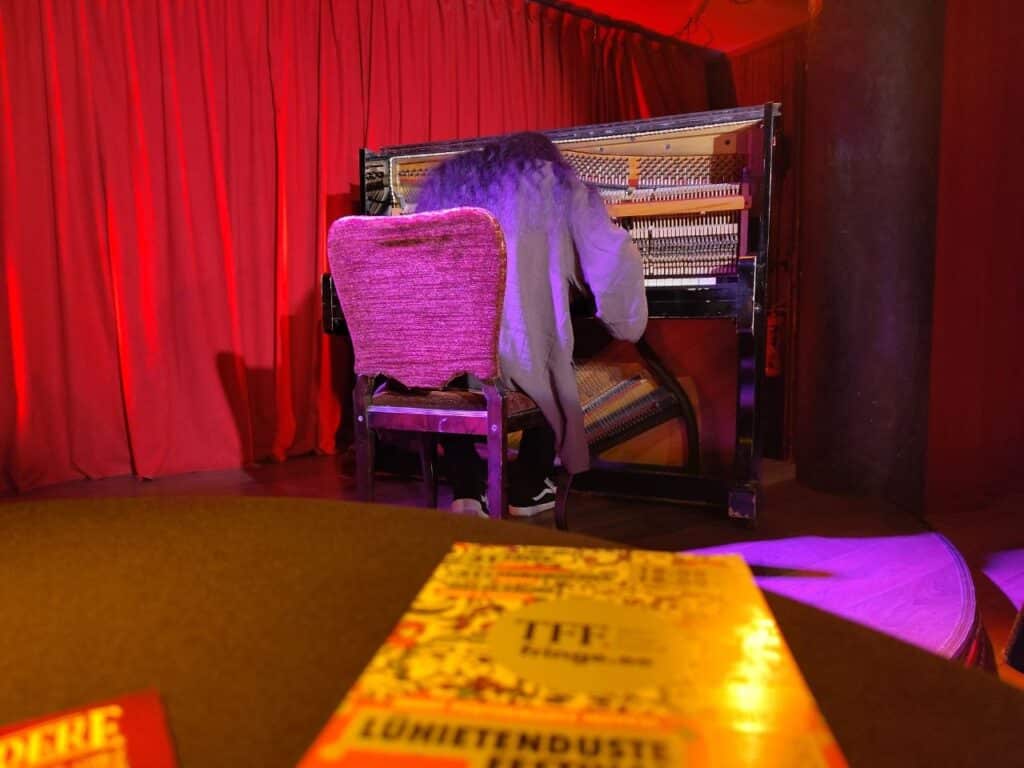 Pianist on the stage performing on an upright piano in cozy venue.