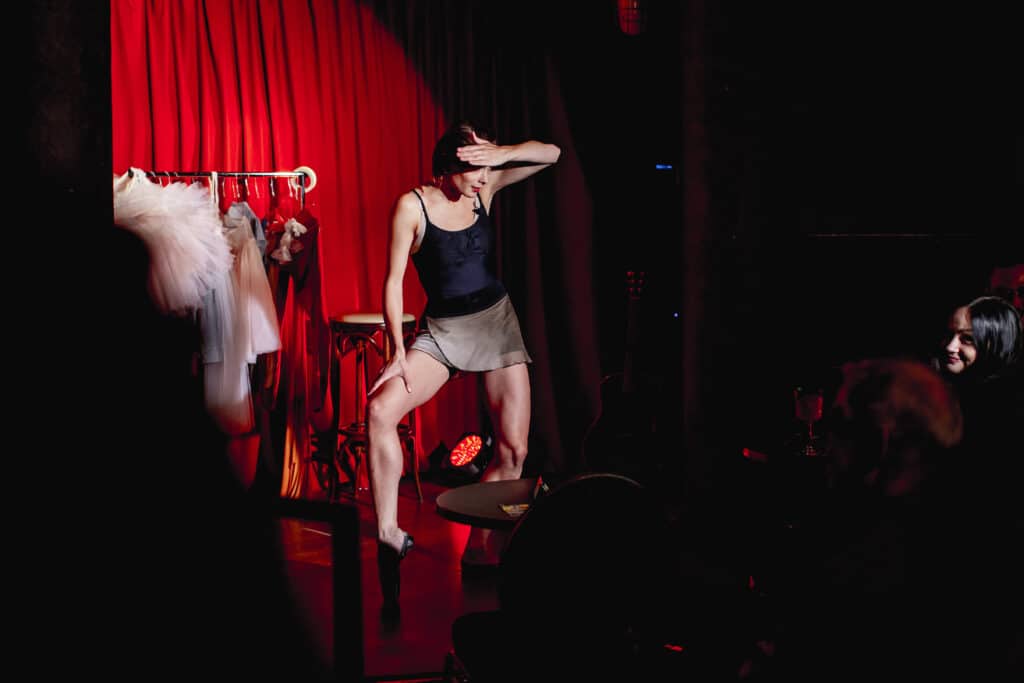 Ballerina on the stage doing a show in Heldeke Kalamaja, with red curtains in the background.